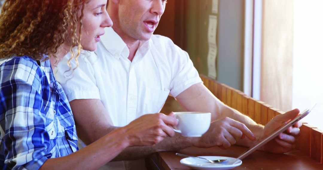Couple Using Tablet While Enjoying Coffee in Cafe