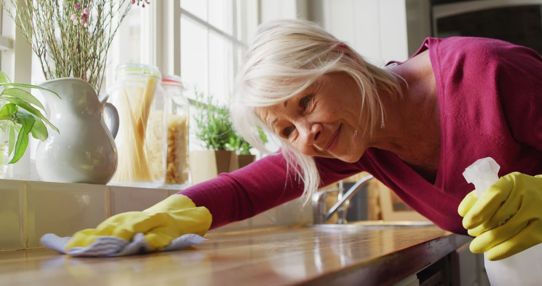 Elderly Woman Cleaning Kitchen Counter with Smile - Free Images, Stock Photos and Pictures on Pikwizard.com