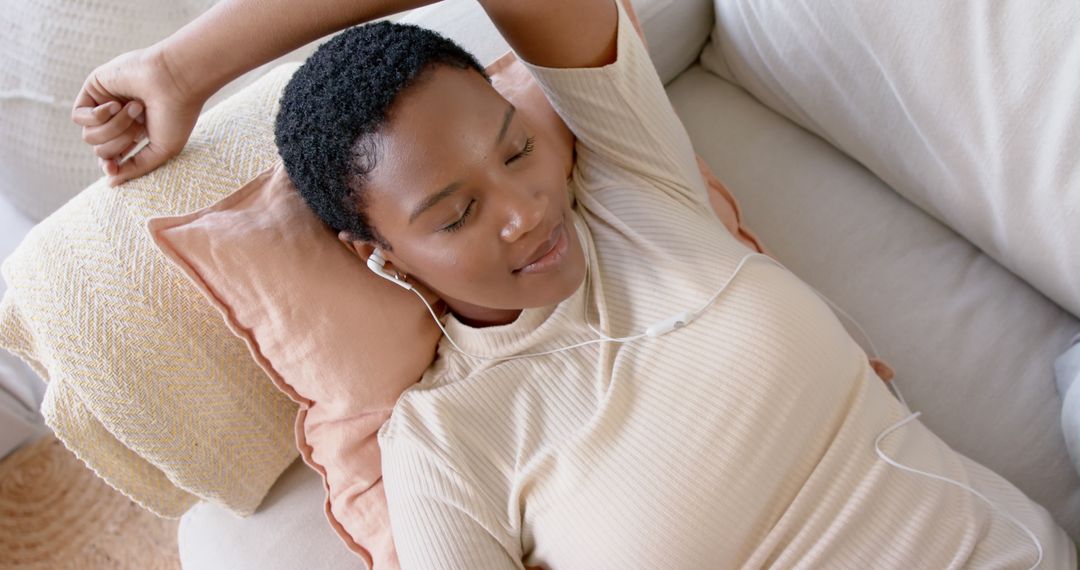 Woman Relaxing on Couch with Earphones Enjoying Music - Free Images, Stock Photos and Pictures on Pikwizard.com