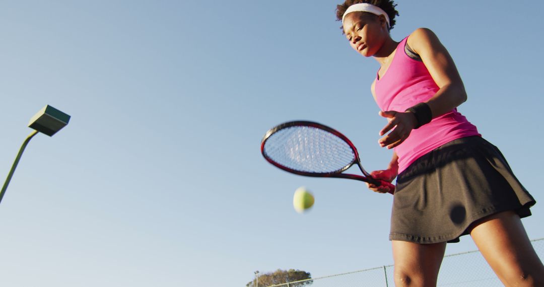 Image of low angle of focused african american female tennis player holding racket and hitting ball - Free Images, Stock Photos and Pictures on Pikwizard.com