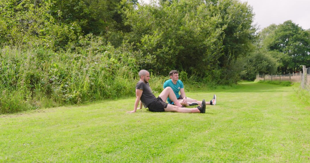Two Men Stretching on Grass Before Jogging in Park