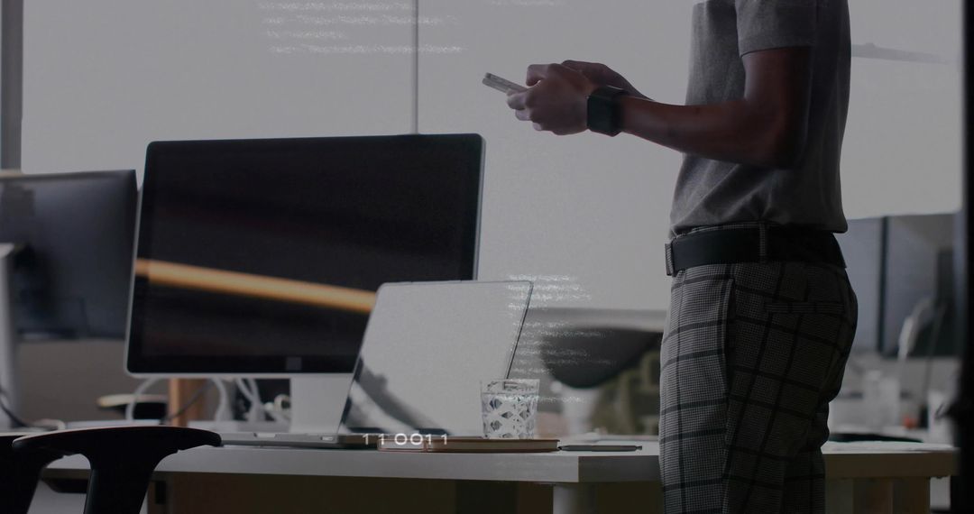 Casual Office Worker Checking Smartphone at Desk with Computer