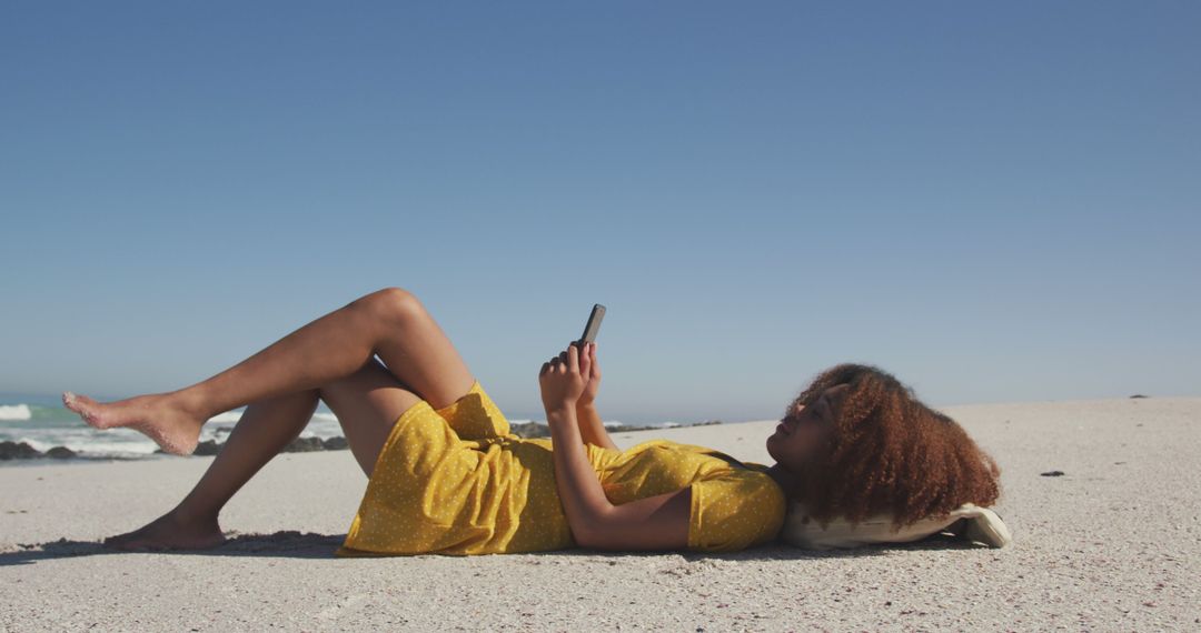 Young woman relaxing on the beach using smartphone - Free Images, Stock Photos and Pictures on Pikwizard.com