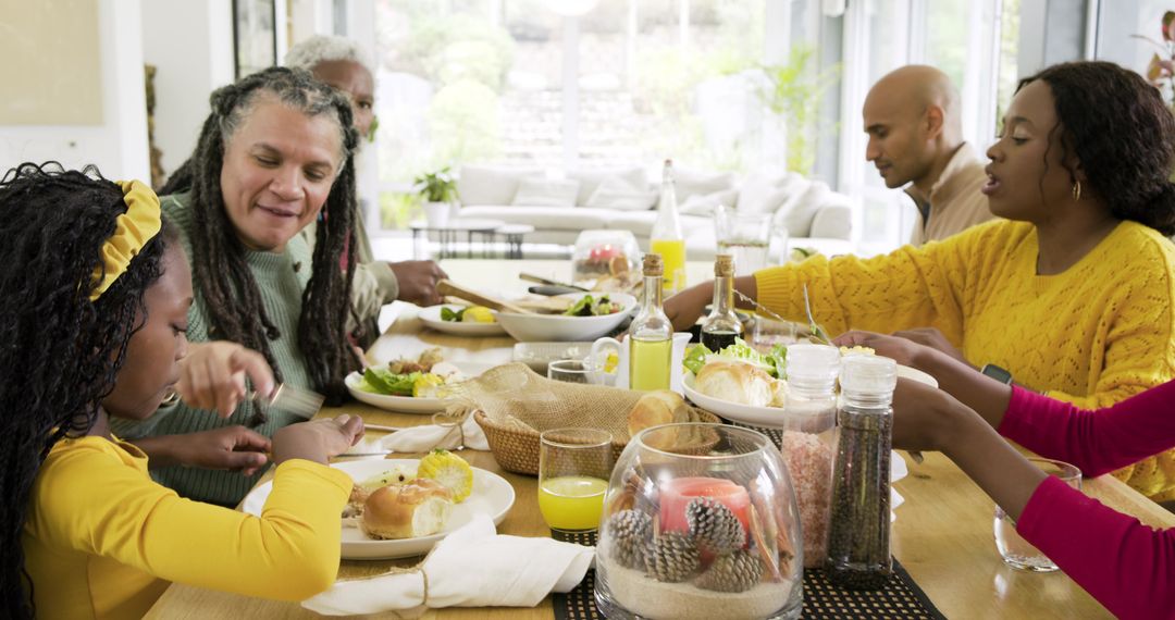 Multigenerational family sharing meal around sunlit wooden dining table passing bread