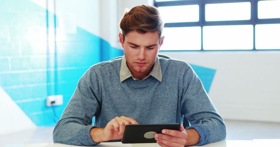 Young Man Using Tablet in Modern Office - Free Images, Stock Photos and Pictures on Pikwizard.com