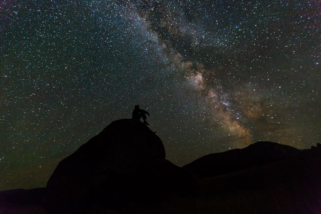 Person Sitting on Rock Under Starry Night Sky with Milky Way Visible - Free Images, Stock Photos and Pictures on Pikwizard.com