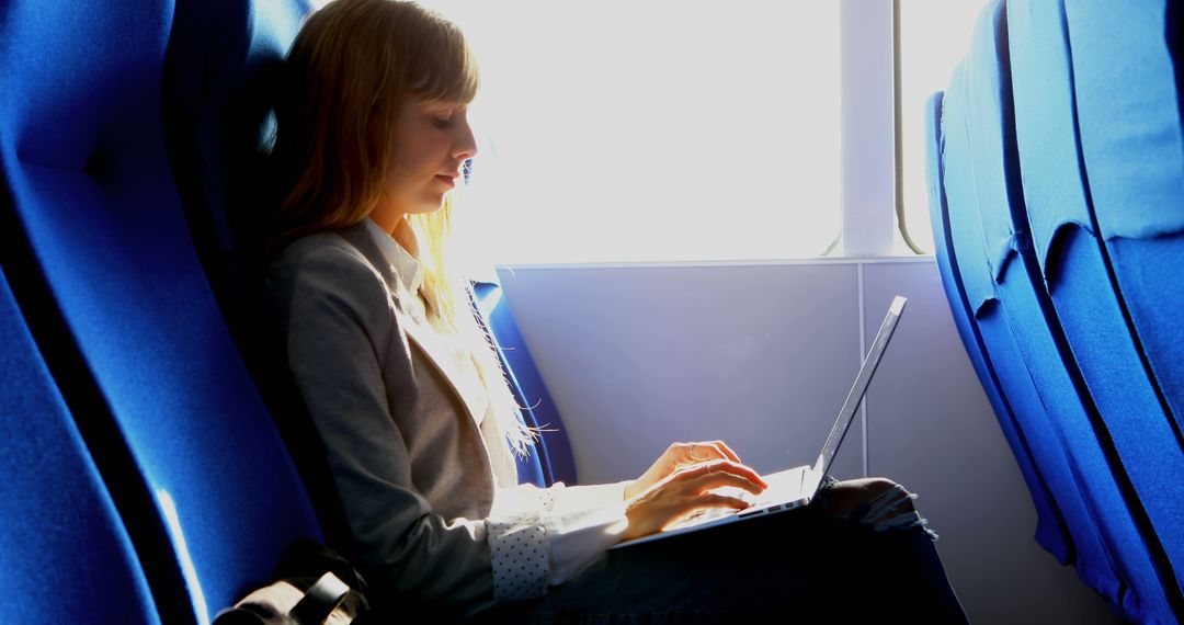 Young Woman Working on Laptop in Sunlit Train - Free Images, Stock Photos and Pictures on Pikwizard.com