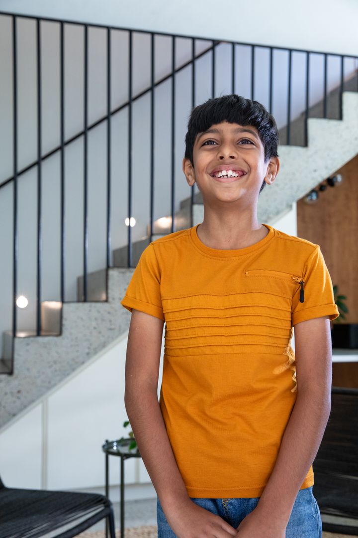 Smiling Asian Boy Standing in Foyer by Modern Staircase