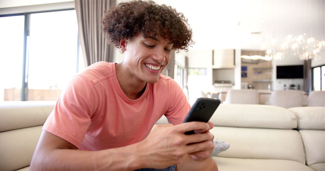 Smiling Man with Smartphone Relaxing on Sofa at Modern Home