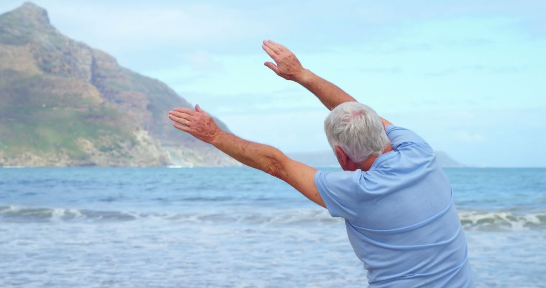 Elderly Man Stretching on Beach with Mountains in Distance - Free Images, Stock Photos and Pictures on Pikwizard.com