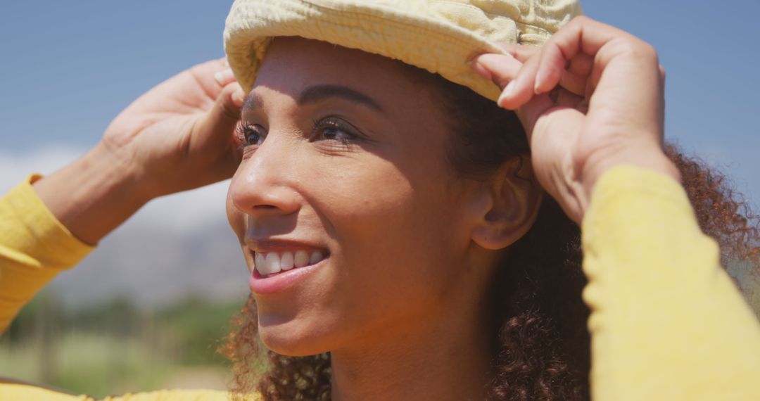 Smiling Woman Adjusting Hat Outdoors - Free Images, Stock Photos and Pictures on Pikwizard.com