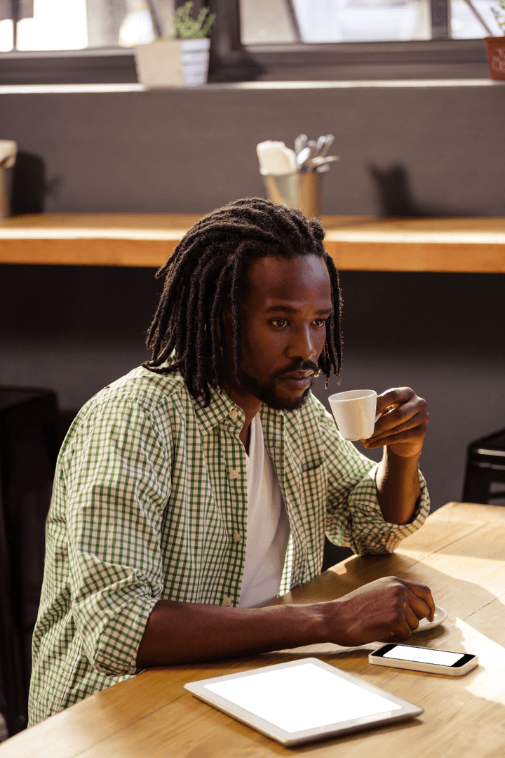 Man with Coffee Cup and Tablet at Wooden Table, Pondering Ideas