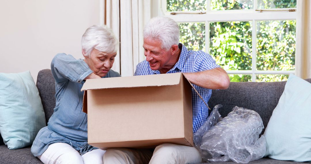 Senior Couple Happy Unboxing Package on Sofa Together