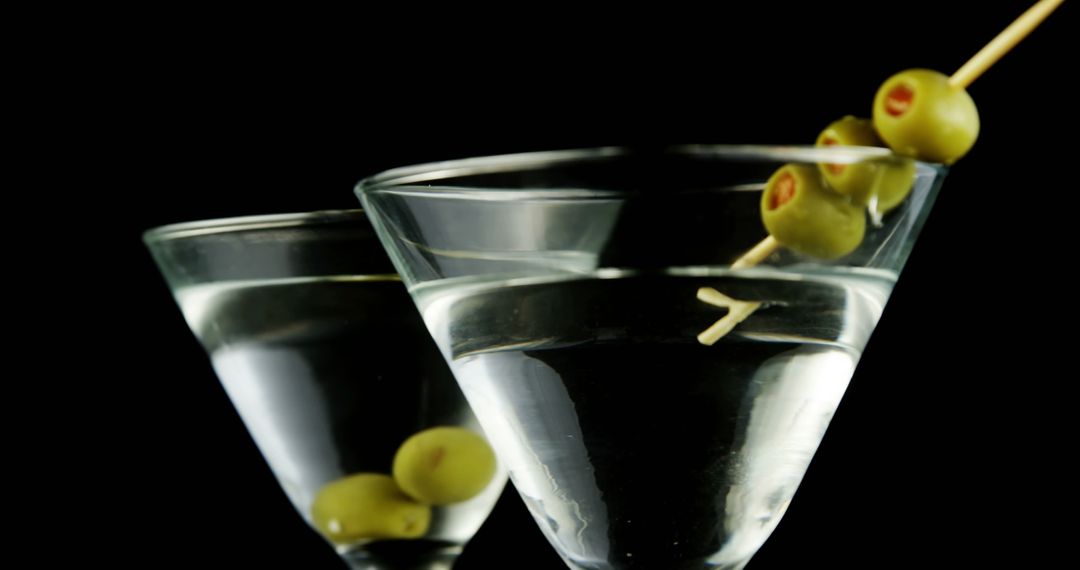 Close-up of martini glasses with olives on black background - Free Images, Stock Photos and Pictures on Pikwizard.com