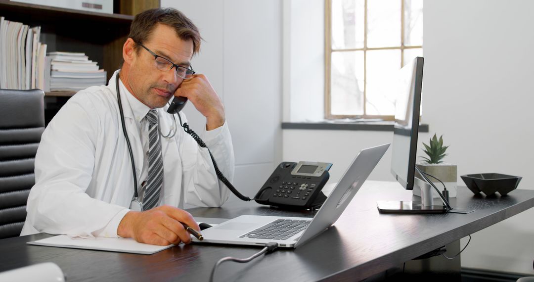 Male Doctor in White Coat and Glasses Taking Phone Call in Office - Free Images, Stock Photos and Pictures on Pikwizard.com