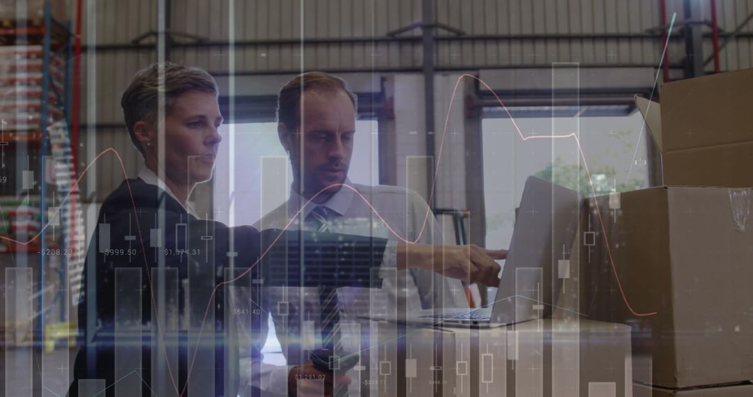 Warehouse Workers Analyzing Financial Data on Laptop
