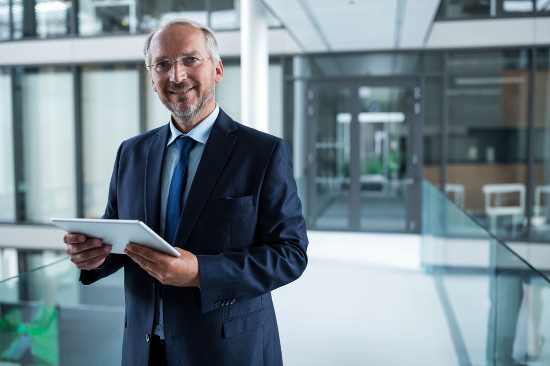 Senior Business Executive with Tablet in Bright Office Atrium