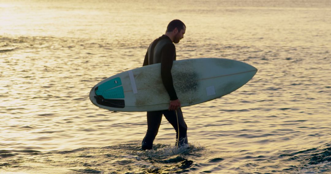Surfer Carrying Surfboard in Ocean During Sunset - Free Images, Stock Photos and Pictures on Pikwizard.com