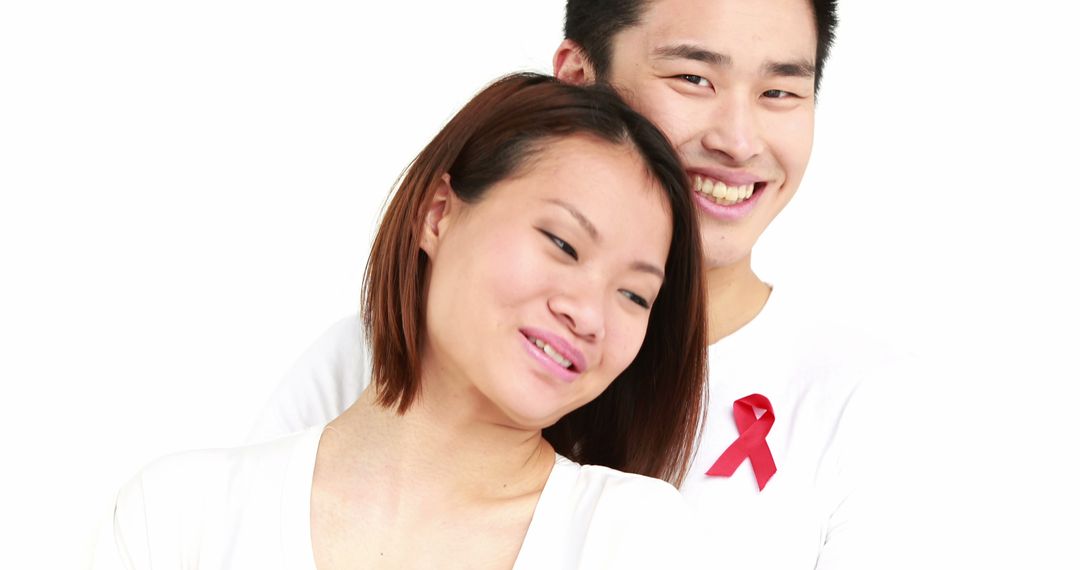 Smiling Asian Couple Promoting HIV/AIDS Awareness with Red Ribbon