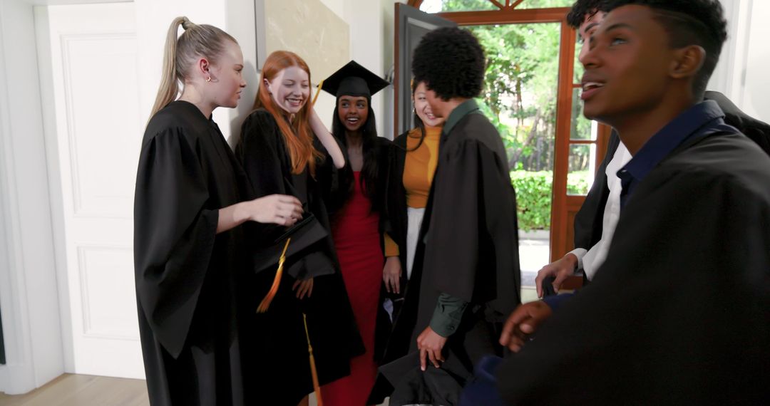 Multicultural Graduates Celebrating and Smiling at Open Doorway Wearing Gowns and Mortarboards