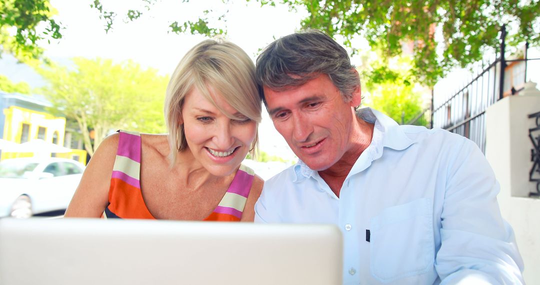 Smiling Middle-aged Couple Using Laptop Outdoors - Free Images, Stock Photos and Pictures on Pikwizard.com