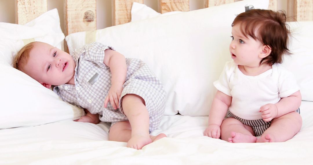 Two Adorable Babies Playing on White Bed - Free Images, Stock Photos and Pictures on Pikwizard.com