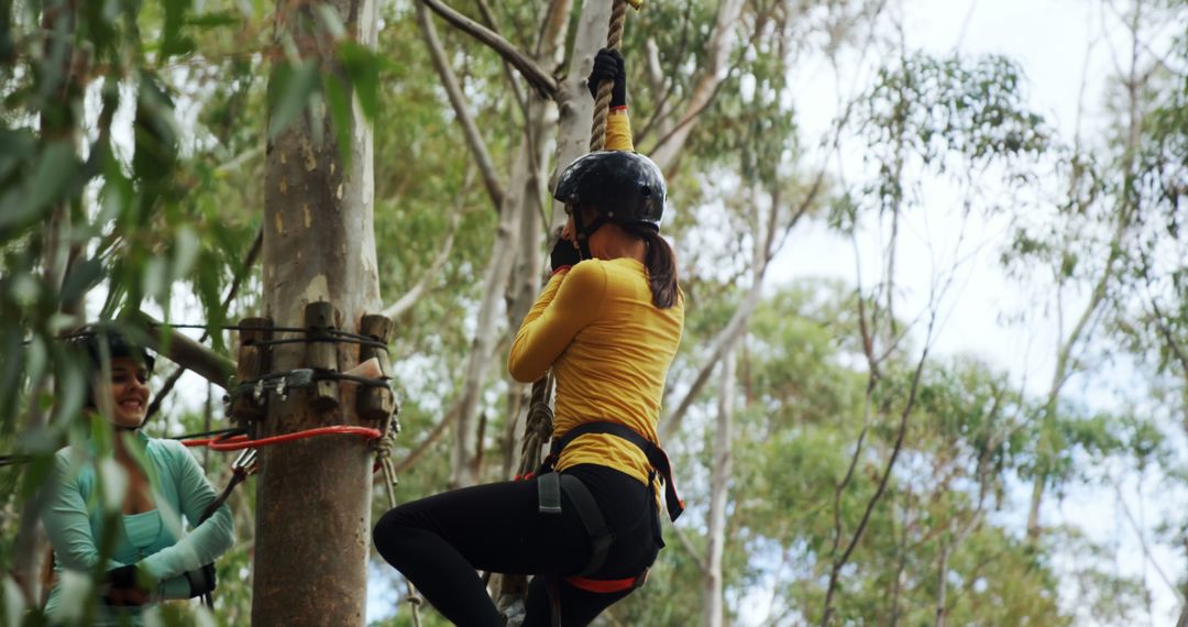 Adventurous Young Woman Climbing in Forest Ropes Course