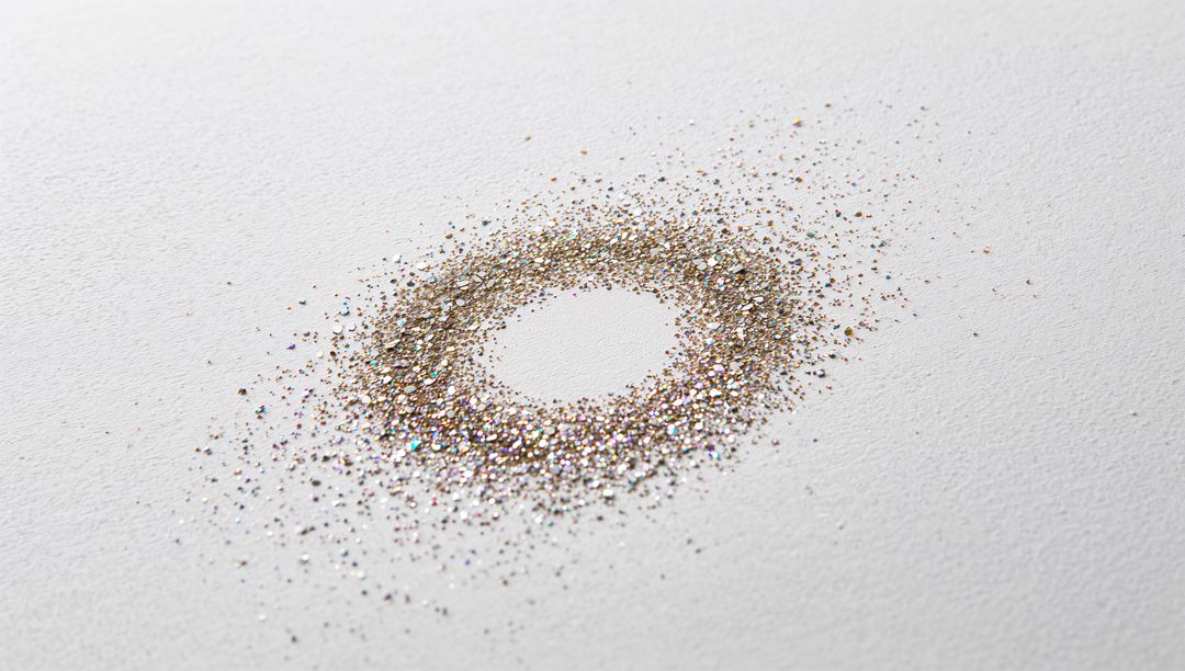 Forming Iridescent Gold Glitter Ring Creating Shimmering Halo on White Paper