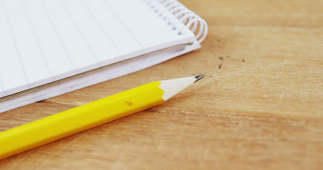 Yellow Pencil and Spiral Notebook on Wooden Desk