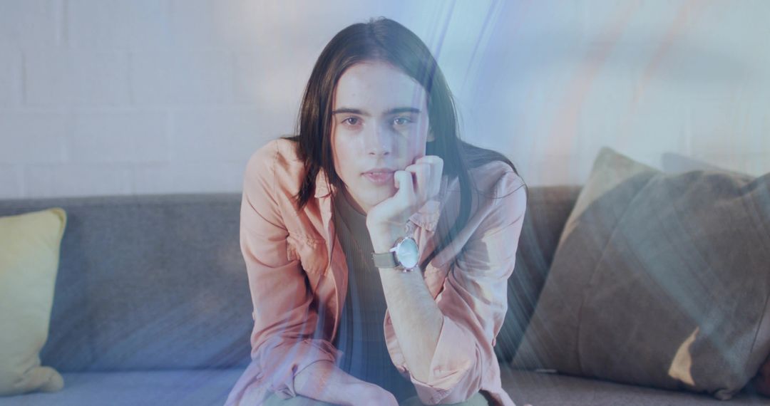 Thoughtful Woman Leaning on Hand Meeting Gaze on Sofa with Soft Light Lens Flare