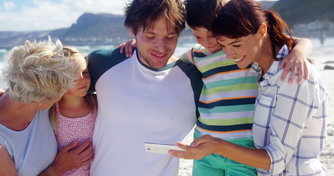 Happy Multigenerational Family Looking at Smartphone on Beach - Free Images, Stock Photos and Pictures on Pikwizard.com