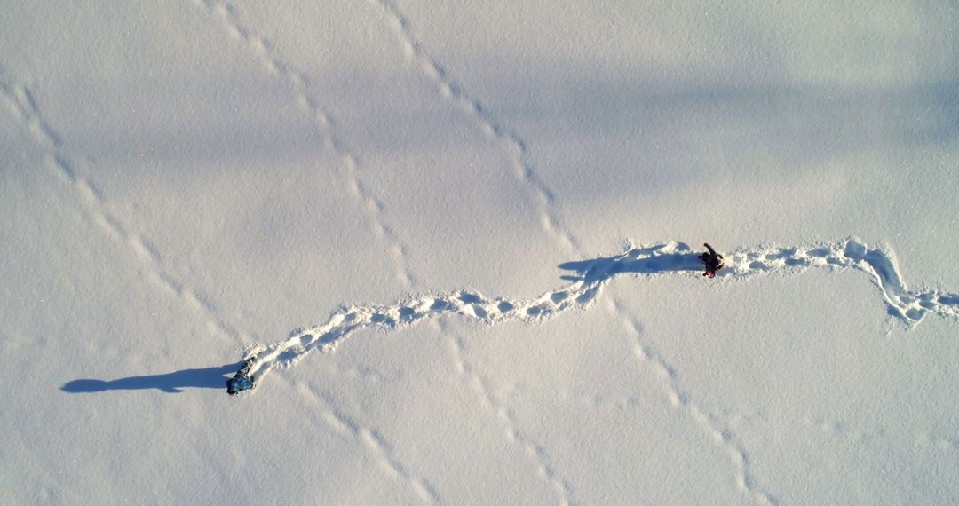 Aerial View of Two People Walking in Snow Leaving Footprints - Free Images, Stock Photos and Pictures on Pikwizard.com