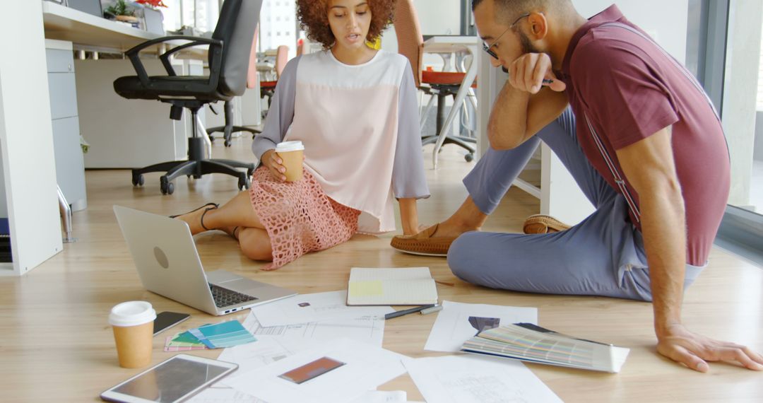 Diverse Team Collaborating on Office Floor with Documents and Laptop