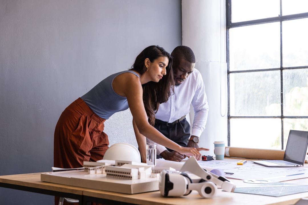 Architects Collaborating on Project Using Laptop and Blueprints