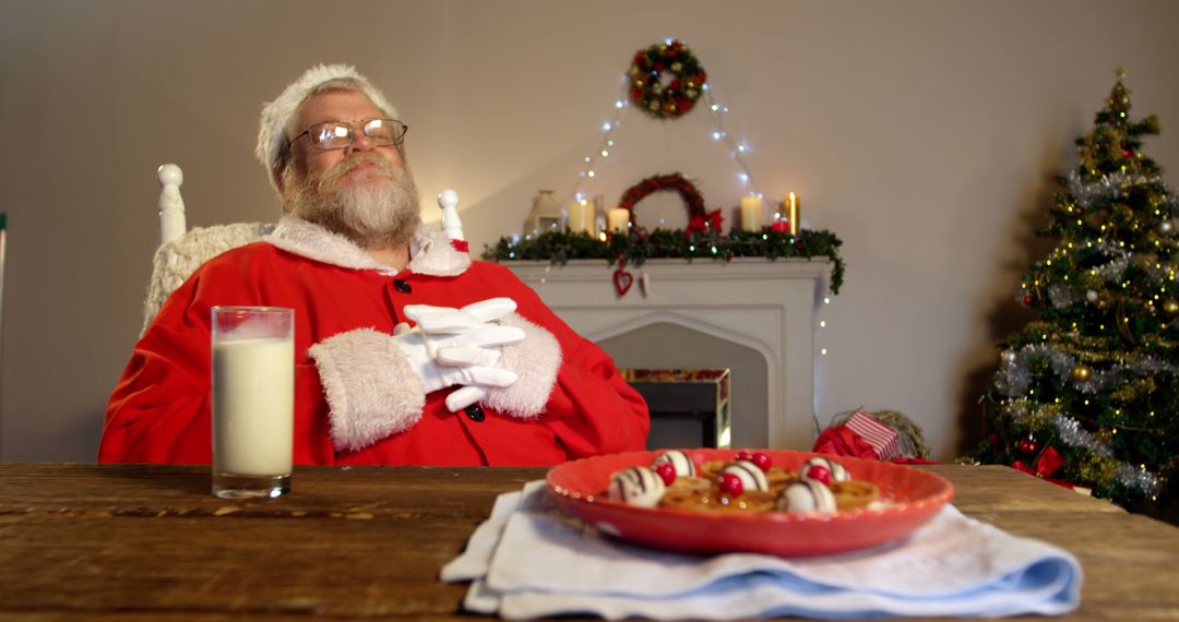 Santa Claus Relaxing by Fireplace with Cookies and Milk During Christmas - Free Images, Stock Photos and Pictures on Pikwizard.com