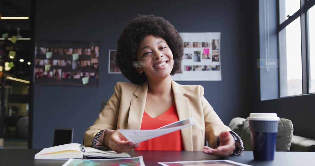 Smiling African American businesswoman handing papers at coworking table, presenting ideas