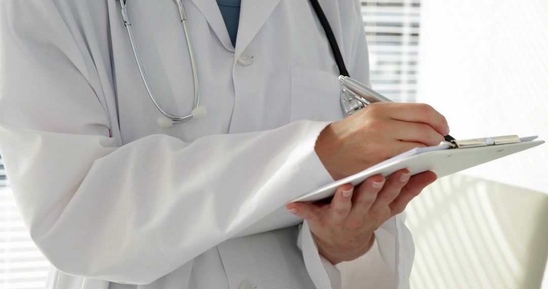 Doctor Writing on Clipboard Holding Stethoscope in Office - Free Images, Stock Photos and Pictures on Pikwizard.com