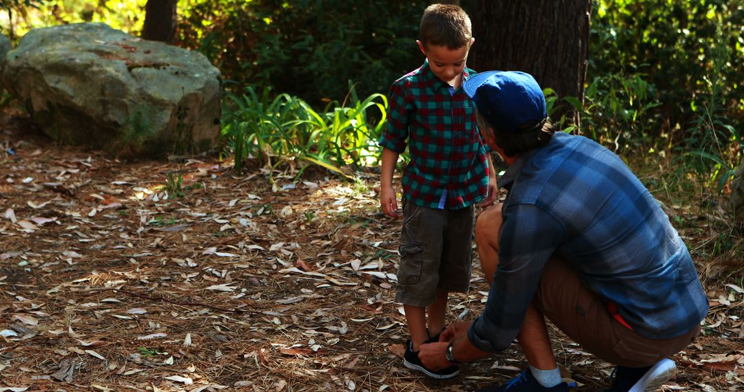 A young boy is having his shoe tied by an adult male in a natural outdoor setting, with copy space - Free Images, Stock Photos and Pictures on Pikwizard.com