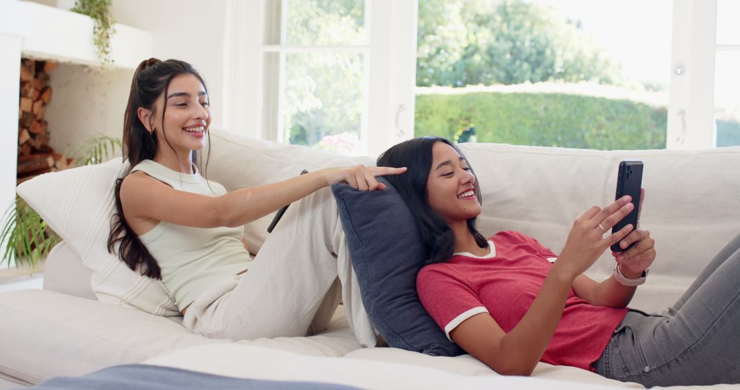 Happy Friends Relaxing on Sofa and Using Smartphone Lounge
