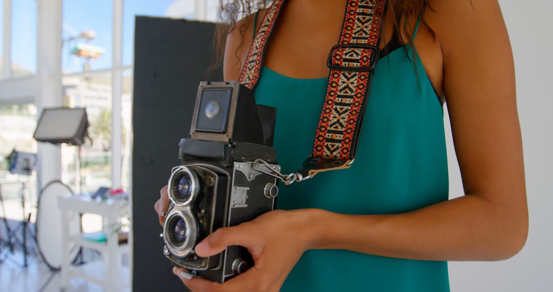 Teenage African American girl holds a vintage camera at home - Free Images, Stock Photos and Pictures on Pikwizard.com
