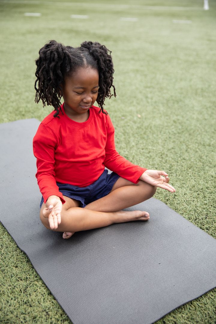 Young African American Girl Meditating Outdoors on Yoga Mat