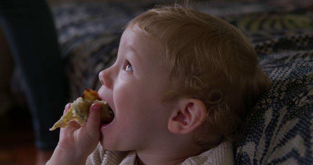 Curious Toddler Eating Snack with Wide Eyes at Home - Free Images, Stock Photos and Pictures on Pikwizard.com