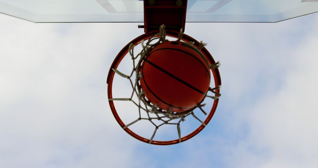 Basketball Dropping Through Hoop From Below With Sky Background - Free Images, Stock Photos and Pictures on Pikwizard.com