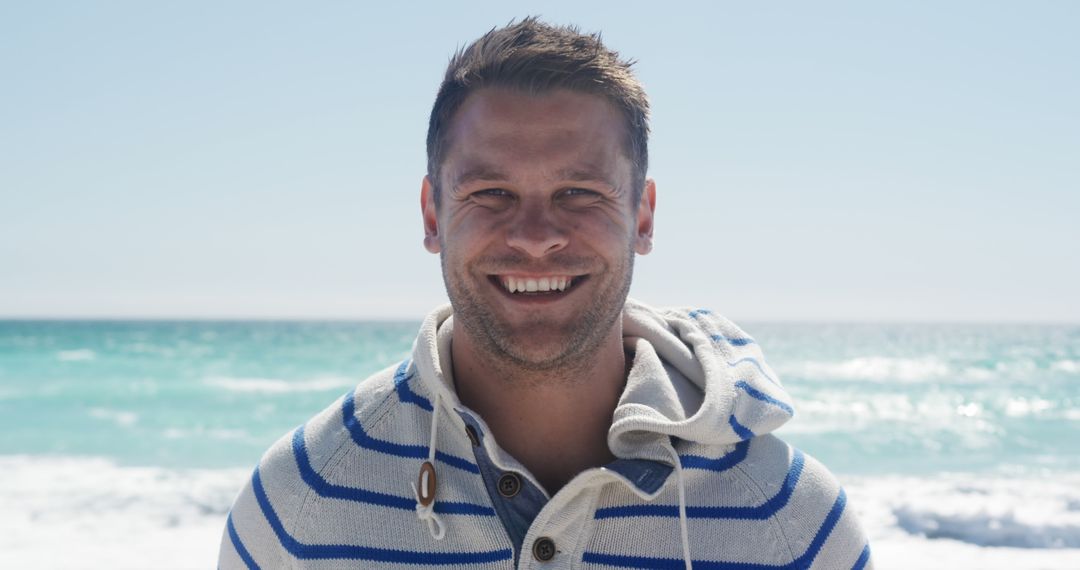 Smiling Man in Striped Hoodie Enjoying Beach on Clear Day - Free Images, Stock Photos and Pictures on Pikwizard.com