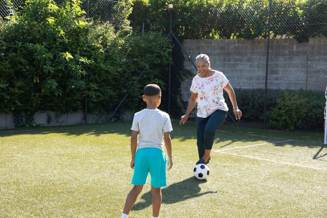 Grandmother Playing Soccer with Grandchild on Turf Field