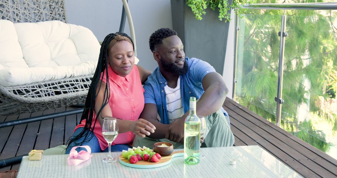 Romantic Couple Enjoying Wine and Fruit on Sunny Balcony Retreat