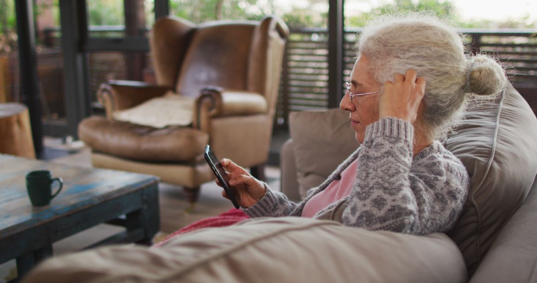 Senior Woman Using Smartphone at Home in Comfortable Living Room - Free Images, Stock Photos and Pictures on Pikwizard.com