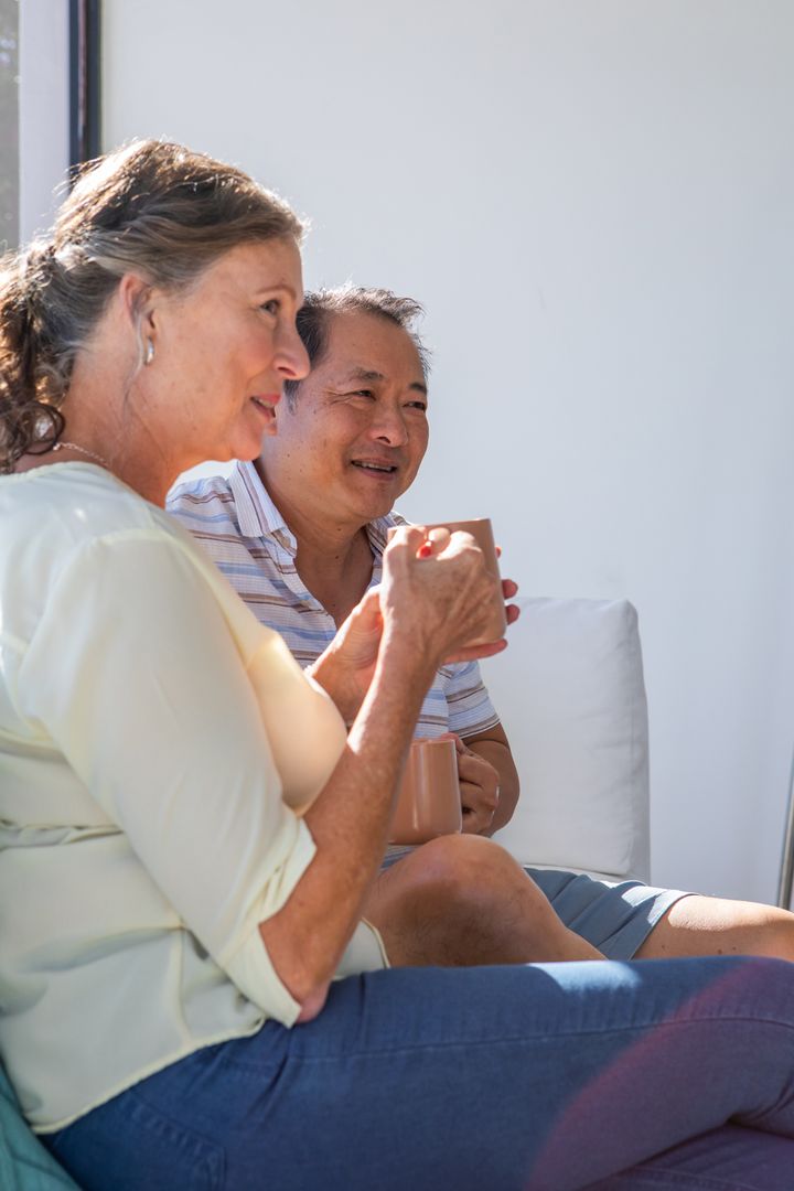 Smiling Senior Couple Relaxing with Coffee on Sunlit Patio