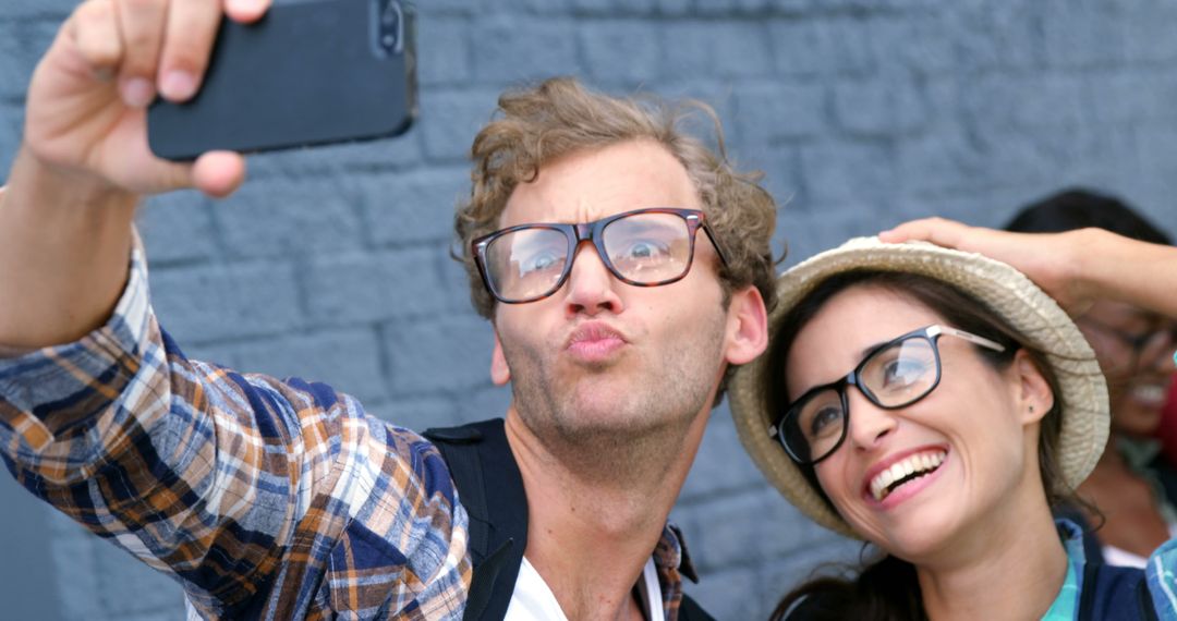 Millennials taking a selfie on street with brick wall background - Free Images, Stock Photos and Pictures on Pikwizard.com