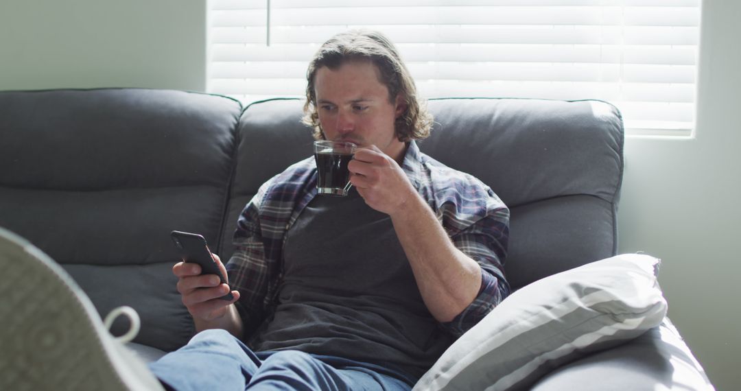 Man Relaxing on Couch with Smartphone and Coffee - Free Images, Stock Photos and Pictures on Pikwizard.com